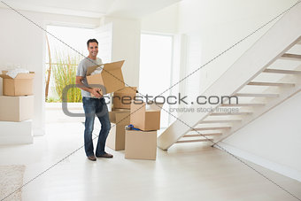 Smiling man carrying boxes in a new house