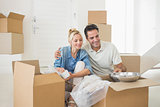 Smiling couple unpacking boxes in a new house