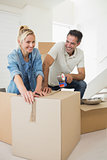 Smiling couple packing boxes in a new house