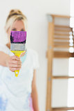 Blurred woman holding out paint brush at new house