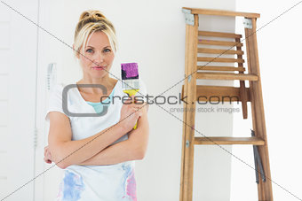 Beautiful woman holding paint brush in new house