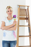 Woman with paint brush looking away in new house