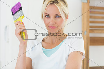 Beautiful woman holding paint brush in new house