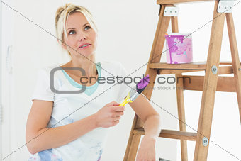 Beautiful woman with paint brush looking away in new house