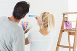 Rear view of a couple choosing color for painting a room