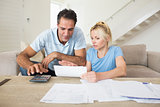 Concentrated couple with bills and calculator in living room