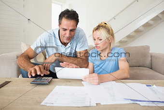 Concentrated couple with bills and calculator in living room
