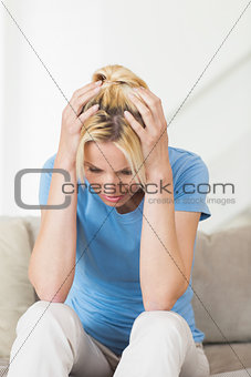 Worried young woman sitting in living room