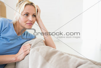 Thoughtful young woman sitting in living room