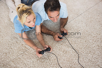 Couple playing video games on area rug at home