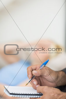 Hands writing diary with blurred woman in background
