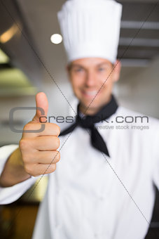 Smiling male cook gesturing thumbs up in kitchen