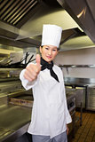 Smiling female cook gesturing thumbs up in kitchen