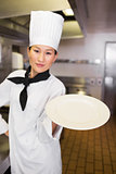 Female cook holding an empty plate in kitchen