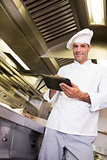 Smiling male cook using digital tablet in kitchen