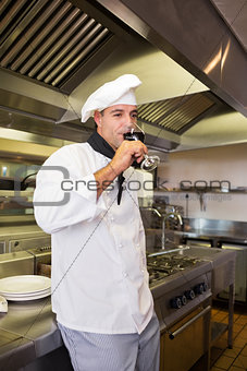 Male cook drinking red wine in kitchen