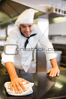 Portrait of a smiling male cook wiping kitchen counter