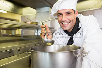 Smiling male cook tasting food in kitchen