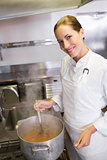 Smiling female cook preparing food in kitchen