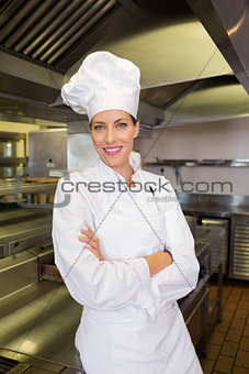 Smiling female cook with arms crossed in kitchen