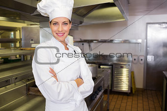 Smiling female cook with arms crossed in kitchen