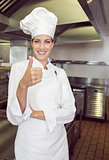 Smiling female cook gesturing thumbs up in kitchen