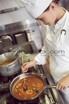 Concentrated female cook preparing food in kitchen