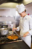 Concentrated female cook preparing food in kitchen