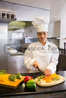 Female chef cutting vegetables in kitchen