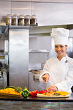 Smiling female chef cutting vegetables in kitchen