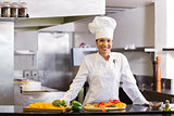 Smiling chef with cut vegetables in kitchen