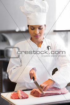 Female chef cutting meat in kitchen
