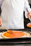 Mid section of a chef preparing pizza in kitchen