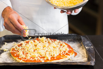 Closeup mid section of a male chef preparing pizza in kitchen