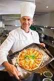 Confident chef holding cooked food in kitchen