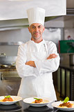 Confident male chef with cooked food in kitchen