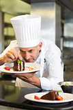Concentrated male pastry chef decorating dessert in kitchen