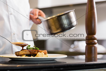 Closeup mid section of a chef garnishing food