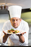 Male chef with eyes closed smelling food in kitchen