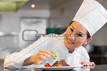 Smiling female chef garnishing food in kitchen