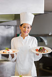 Confident female chef holding cooked food in kitchen
