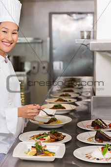 Smiling female chef garnishing food in kitchen