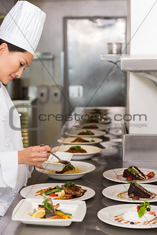 Female chef garnishing food in kitchen