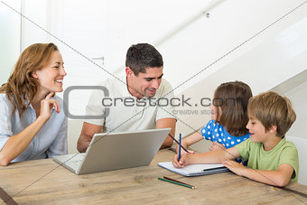 Parents with laptop assisting children coloring