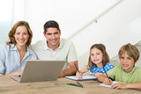 Parents with laptop while children coloring at table