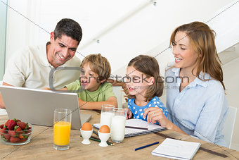 Family using laptop while having breakfast