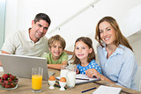 Portrait of family using laptop while having breakfast