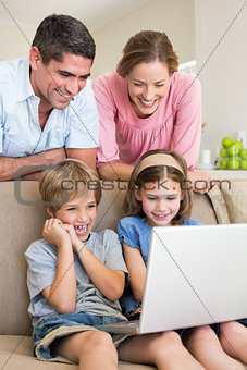 Parents watching children using laptop