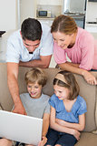 Parents teaching children to use laptop