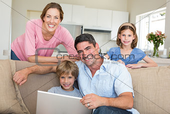 Smiling family using laptop in sitting room